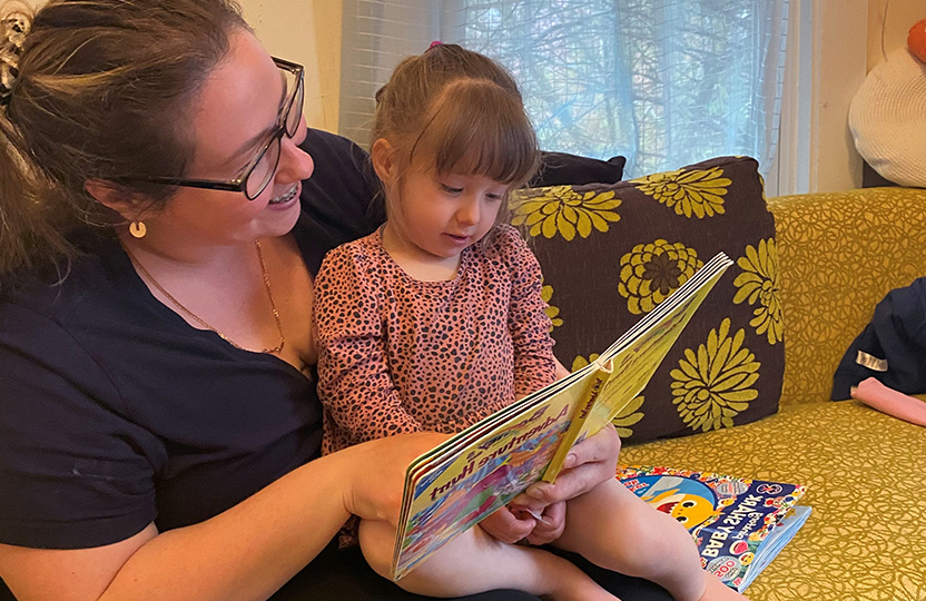 Parent reading a book to daughter