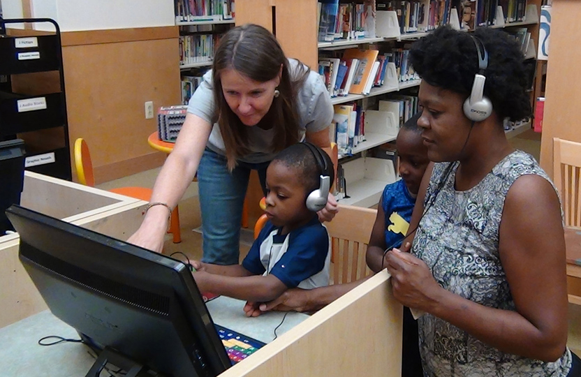Teacher showing student and family how to use assistive technology