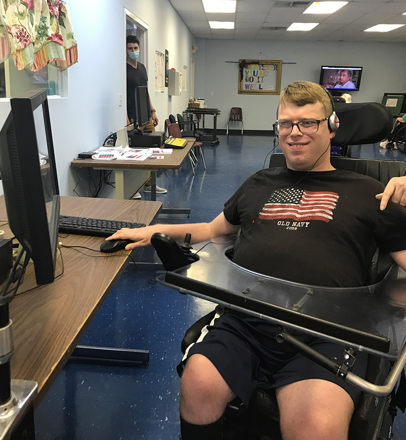 Man in a wheel chair where headphones while on the computer