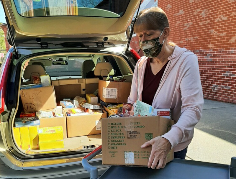 Volunteer taking boxes of donation items out of her car's trunk